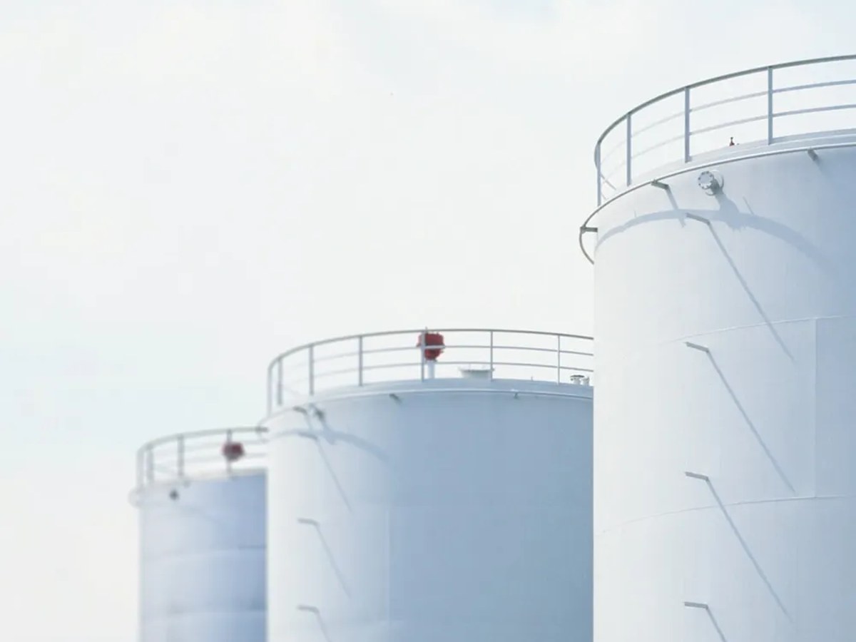 Rows of white bulk petroleum storage tanks under a clear blue sky