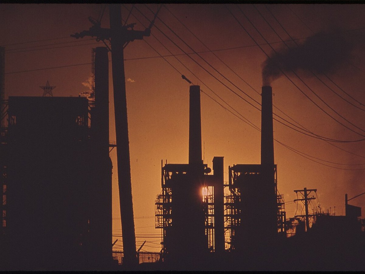 Oil refinery silhouetted against an orange sunset sky